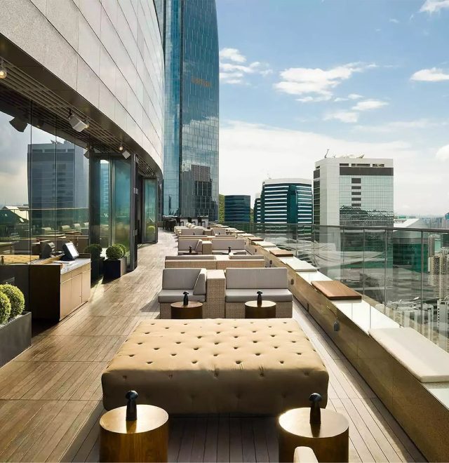 Cosy seating dining area with sofa like chairs and tables along a grand balcony high up a luxury building