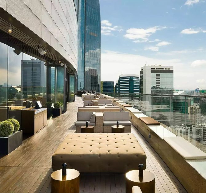 Cosy seating dining area with sofa like chairs and tables along a grand balcony high up a luxury building
