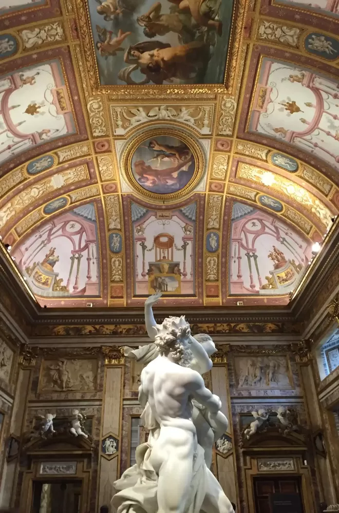 White sculpture of naked man and women below huge walls and cielings covered in various colourful artwork and gold trims